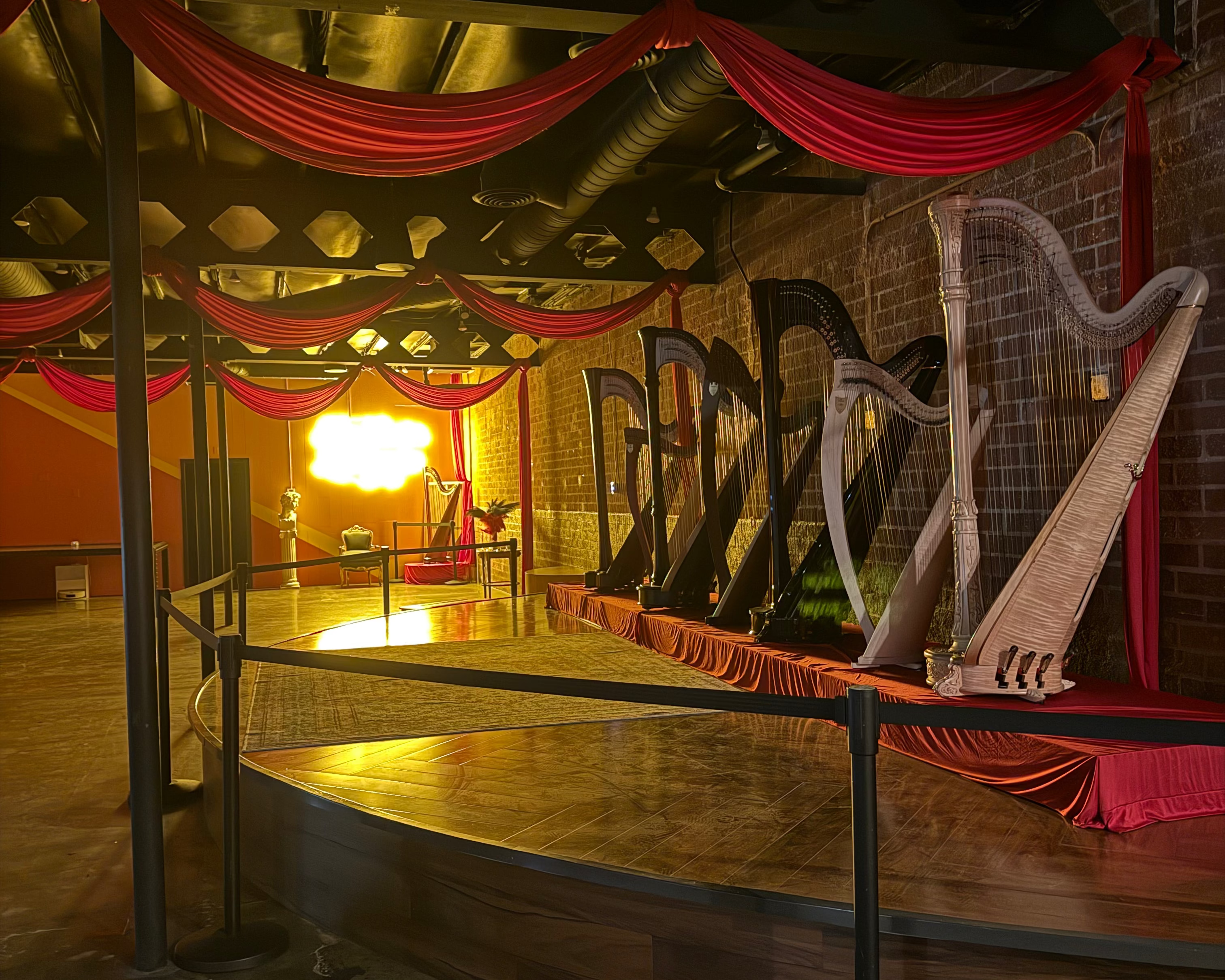 Indoor setting with a harp, draped fabric, and a light fixture.